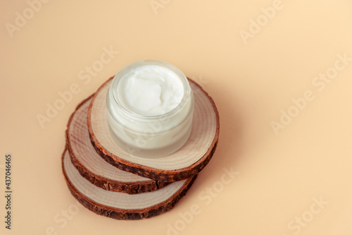 Cream jar on wooden stand on beige table. Natural organic cosmetics concept. Top view