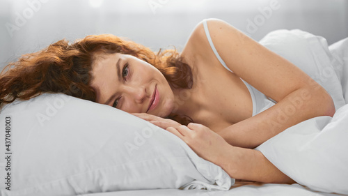 happy young woman lying on pillow and looking at camera