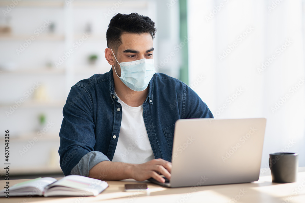 Arab man in protective face mask using laptop Arab man in protective face mask using laptop