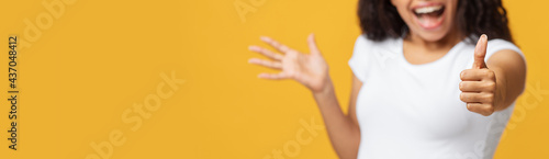 Wow, i lke it. Unrecognizable happy black lady showing thumb up over yellow background, panorama with empty space