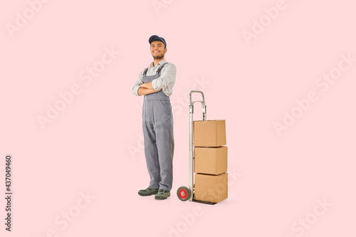 Self confident delivery man with hand truck trolley brown cardboard box style. Colorful background.