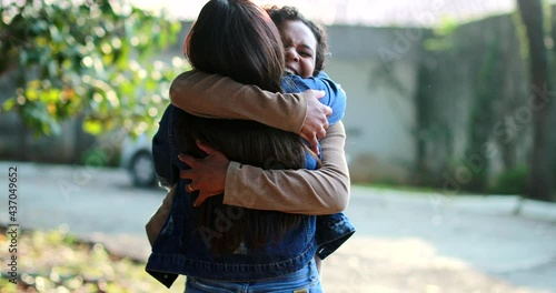 Two female friends hug and embrace outside, real life happiness reunion photo