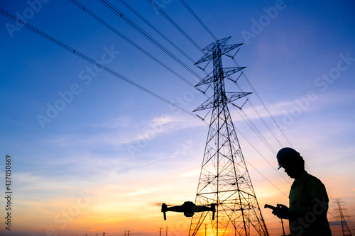 Silhouette of an electrical engineer flying a drone inspecting electricity at the station to see work Planned by producing power at the high voltage electrodes.