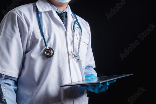 A male doctor standing with a tablet Taken on a black background Concept of technology in medicine