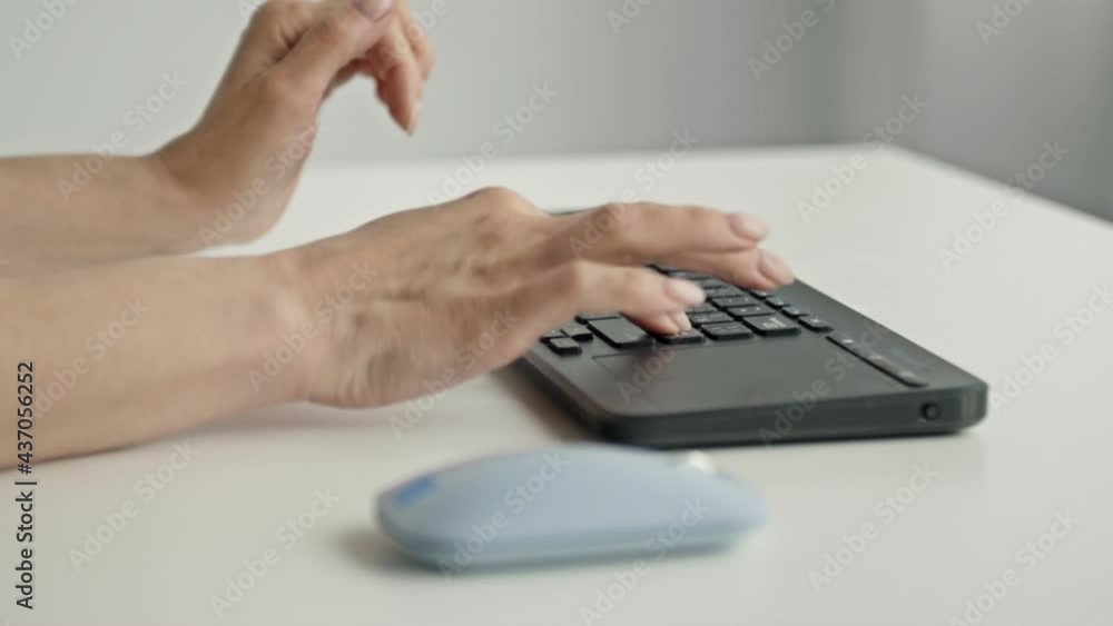 Female hands typing on keyboard and holding computer mouse on light background Female hands typing on keyboard and holding computer mouse on light background