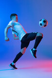 Young Caucasian man, male soccer football player training isolated on gradient blue pink background in neon light