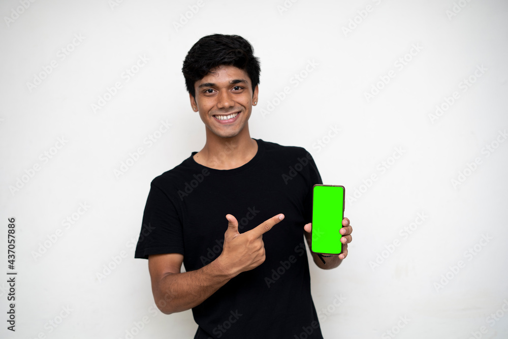 Young indian boy holding a mobile phone and point towards it's screen. Mobile phone with a green screen for mockup. Young indian boy holding a mobile phone and point towards it's screen. Mobile phone with a green screen for mockup.