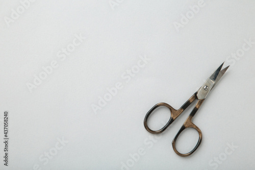 Small metal manicure scissors on grey background with copy space