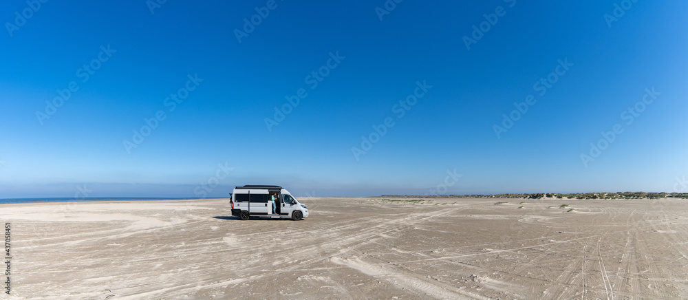 panorama of a gray camper van parked on an endless white sand beach in the middle of nowhere with ocean behind panorama of a gray camper van parked on an endless white sand beach in the middle of nowhere with ocean behind