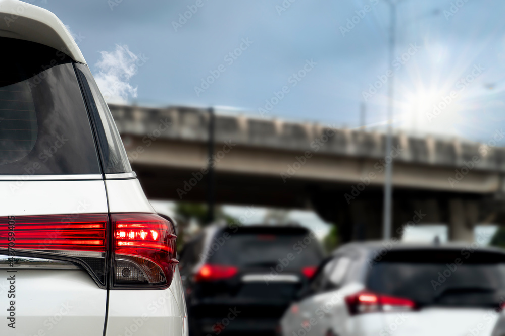 Close-up trail light of white car on the road heading towards the goal of the trip. During the daytime rush traffic. There is a level bridge on the front.