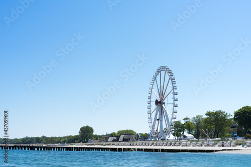 View of the coast from the water, a summer day on the beach with beach chairs, ferris wheel and groynes