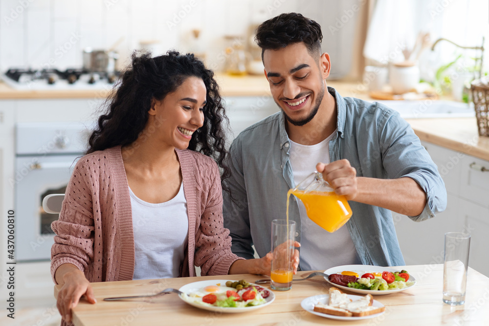 Morning Meal. Arab Spouses Eating Breakfast And Drinking Orange Juice In Kitchen Morning Meal. Arab Spouses Eating Breakfast And Drinking Orange Juice In Kitchen