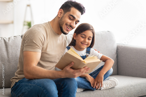 Father and daughter reading book spending time together at home