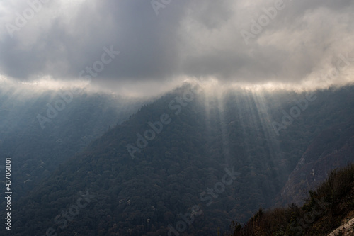 mountain range with sun ray beams and heavy cloud overcast at day