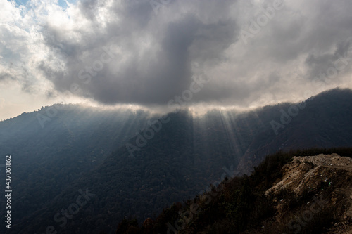 mountain range with sun ray beams and heavy cloud overcast at day