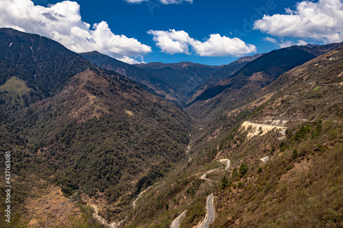 mountain valley with curvy road and bright blue sky at sunny day from top photo