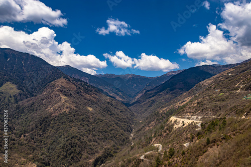 mountain valley with curvy road and bright blue sky at sunny day