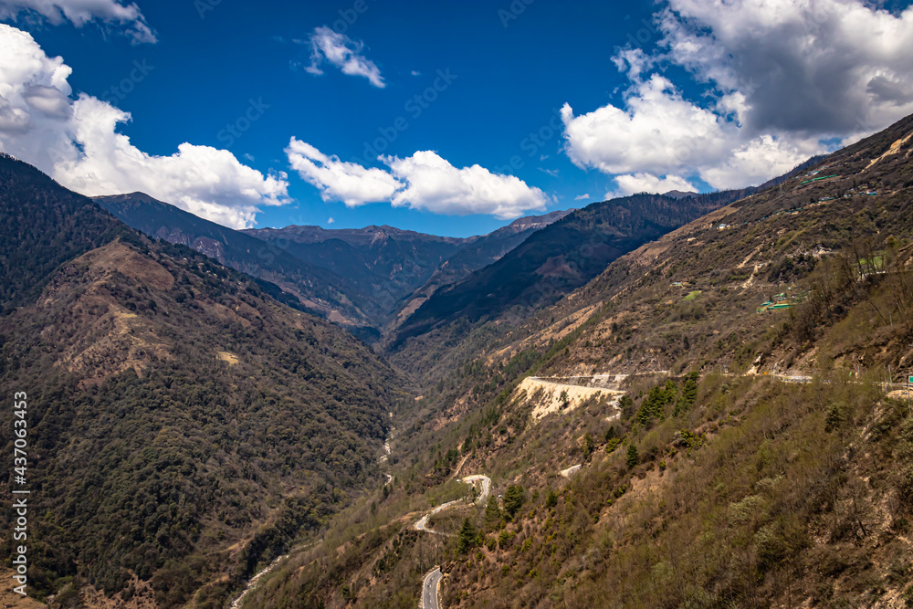 mountain valley with curvy road and bright blue sky at sunny day