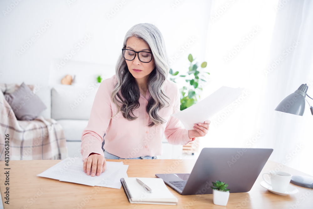 Photo of focused serious old woman look table paper documents laptop job indoors inside house home flat Photo of focused serious old woman look table paper documents laptop job indoors inside house home flat
