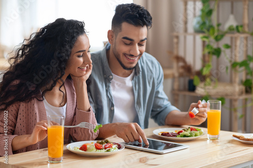 Middle-Eastern Couple Shopping Online With Digital Tablet While Having Breakfast In Kitchen