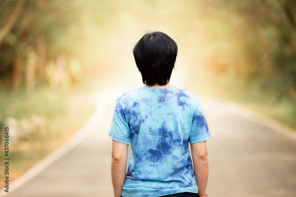 Fototapeta premium woman stand on the road with tree around, Asian traveler girl stand turn back on the road with sunshine and tree of parkland