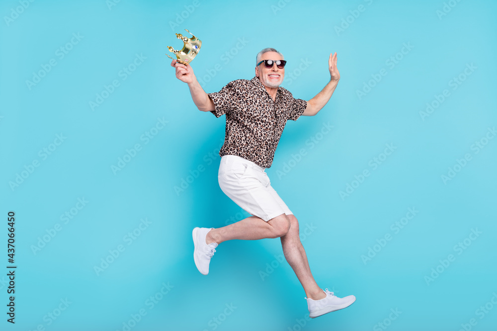 Full size photo of attractive cool old man jump up air hold hand crown summer isolated on blue color background