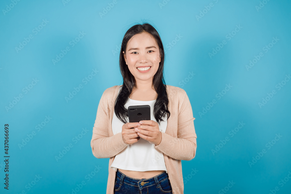 Portrait of smiling Asian woman using a smartphone isolated on blue background Portrait of smiling Asian woman using a smartphone isolated on blue background