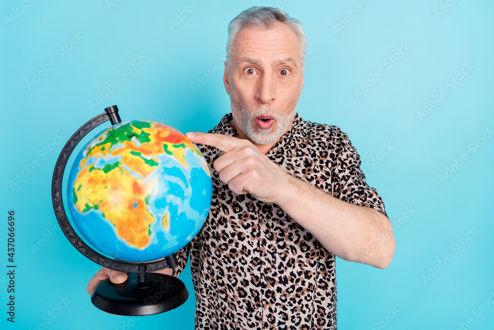 Photo of amazed shocked old man point finger globe tourist destination isolated on blue color background Photo of amazed shocked old man point finger globe tourist destination isolated on blue color background