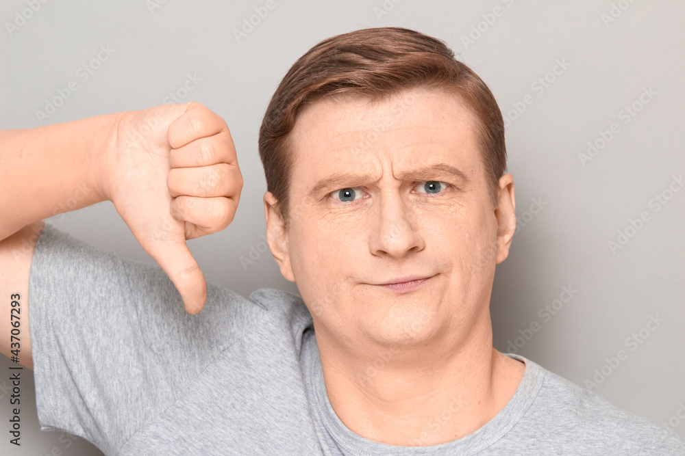Portrait of unhappy disgruntled man giving thumb down sign of dislike Portrait of unhappy disgruntled man giving thumb down sign of dislike