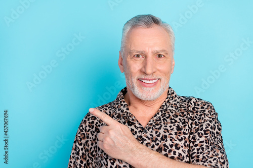 Photo of positive happy old man smile point finger empty space good product isolated on blue color background