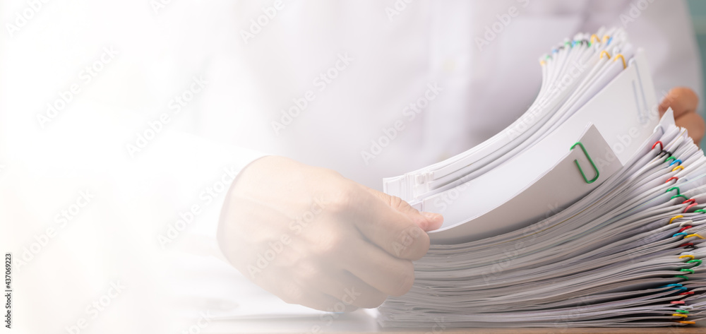 Business man hand pick up Stack overload document report paper with colorful paperclip