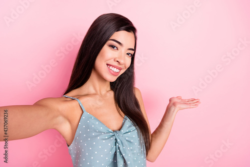 Photo of attractive pretty young woman hold hands empty space invite make selfie isolated on pink color background © deagreez
