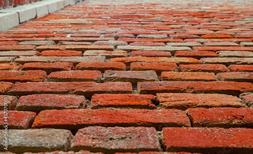 Wall of old red brick with weathered cement. At an angle