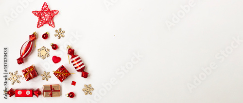 Flat composition with a Christmas tree made of different festive items, snowflakes, gifts, sweets on a white background. Copy space
