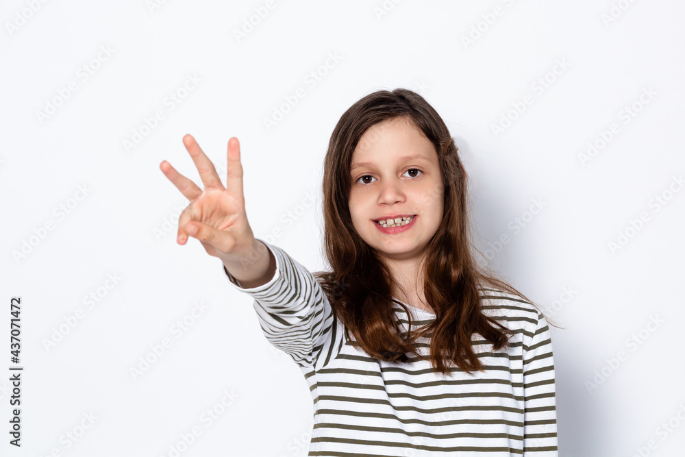A funny dark-haired girl shows three fingers on her hand. Digit 3. Portrait on a light background. Place for your text. A funny dark-haired girl shows three fingers on her hand. Digit 3. Portrait on a light background. Place for your text.