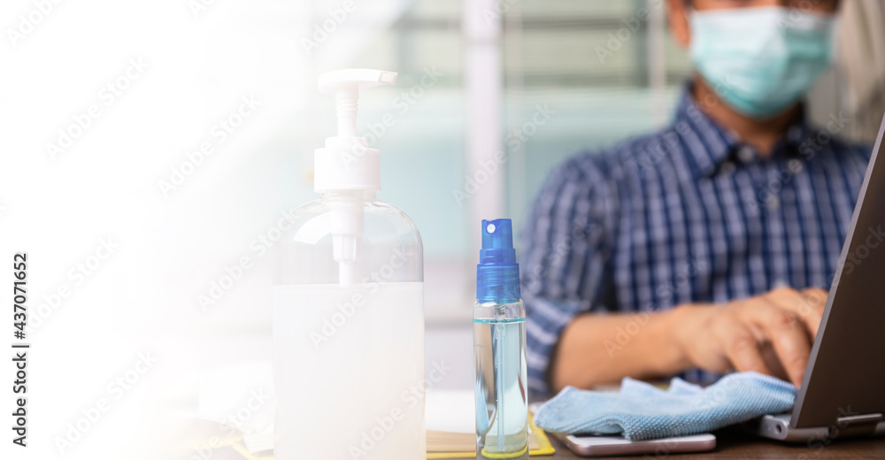 Alcohol gel to prevent corona virus covid-19 infection with male employee working in back. Alcohol gel to prevent corona virus covid-19 infection with male employee working in back.