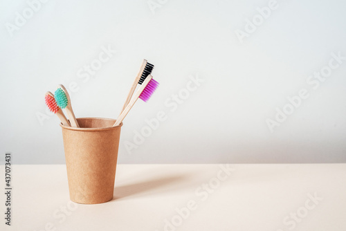 Multicolored eco friendly bamboo toothbrushes in paper cup, dental care with zero waste concept, sustainable lifestyle