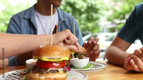 Group of friends  sitting in street fast food restaurant and eating burgers.	

