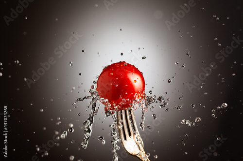 Cherry tomatoes on a metal fork. Splashes of water. Black white background