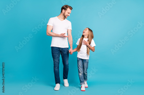 Full body portrait of positive guy cheerful girl hold hands look each other tell funny story isolated on blue color background