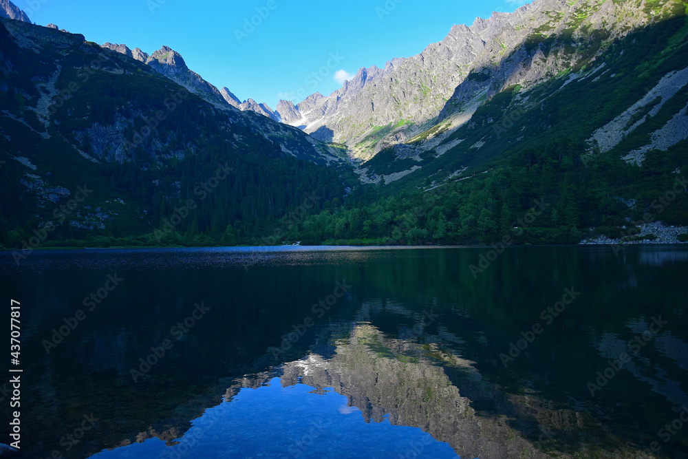 The beautiful lake Popradske pleso in the High Tatras in the evening sun with a reflection of the mountains. Slovakia.
