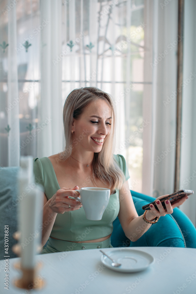 An attractive woman at a table in a cafe communicates on a smartphone. An attractive woman at a table in a cafe communicates on a smartphone.