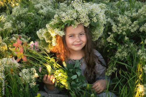 Portrait of a little girl in a wreath of field herbs
