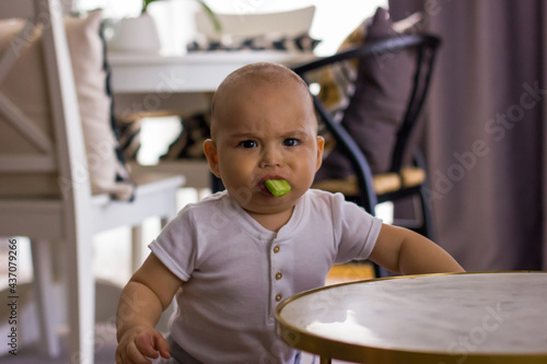 Funny baby with cucumber in his mouth. Organic food, properly and healthy feeding. Very serious babyface photo