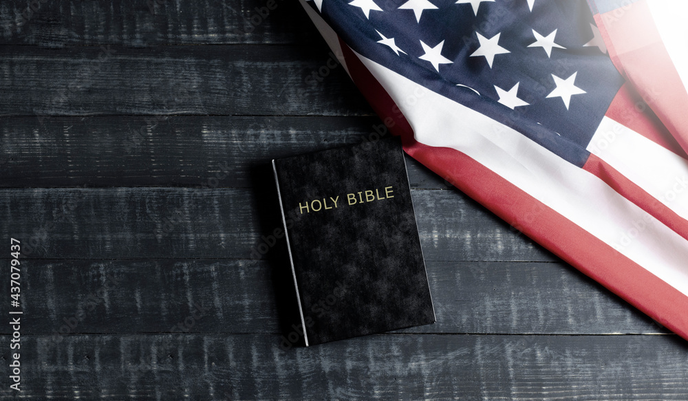 Fototapeta premium United States of America flag. Black Bible book on wooden background. Constitution.