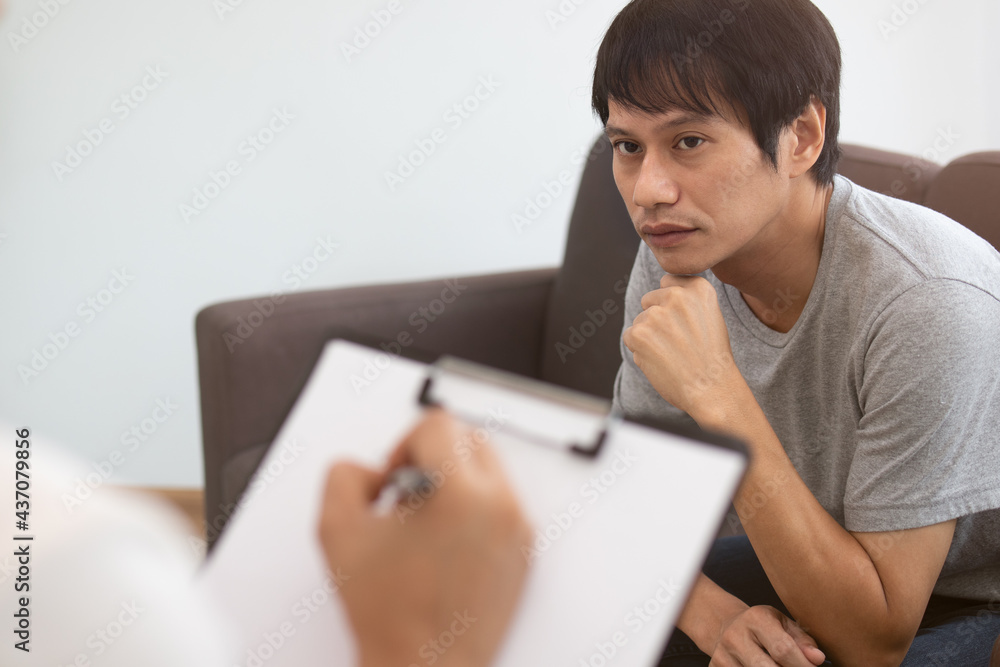 Sick,illness Asian young man mental symptom which must have been therapy, stress, sit on couch consult with psychologist, doctor woman take notes treat by therapist at clinic. Health care, sad person. Sick,illness Asian young man mental symptom which must have been therapy, stress, sit on couch consult with psychologist, doctor woman take notes treat by therapist at clinic. Health care, sad person.
