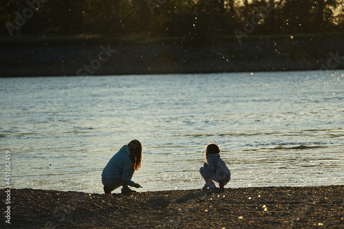 Closeup shot of kids playing on the lake shore during sunset