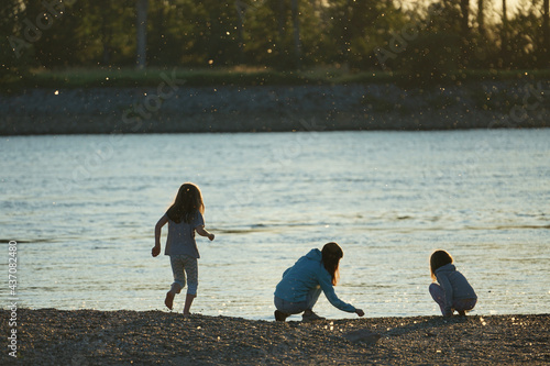 Closeup shot of kids playing on the lake shore during sunset