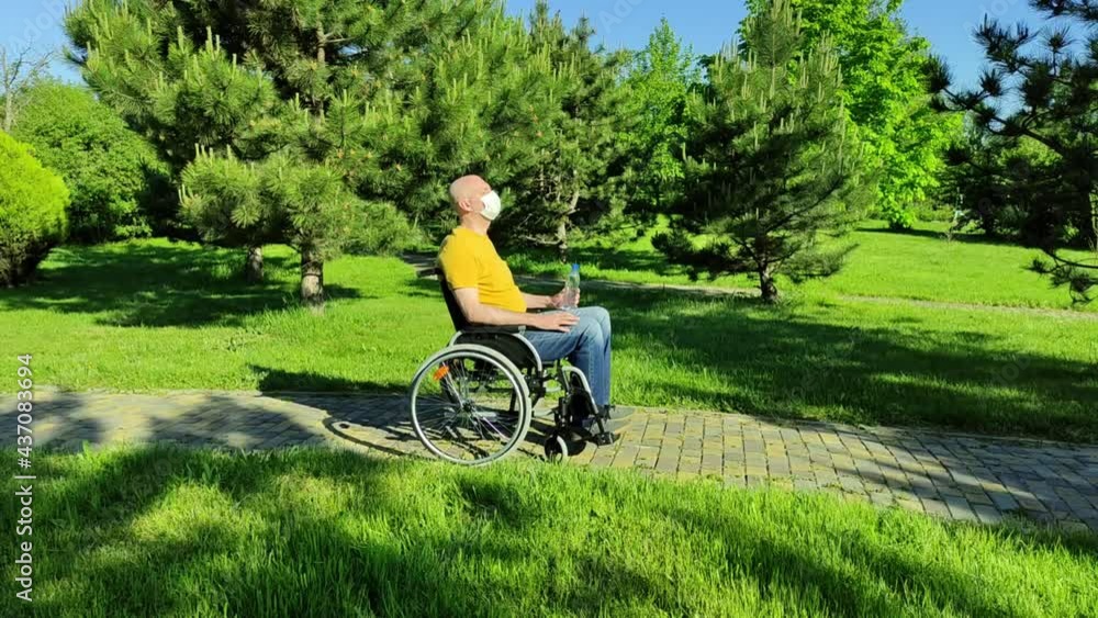 Disabled person resting in the park while sitting in a wheelchair. High quality 4k footage Disabled person resting in the park while sitting in a wheelchair. High quality 4k footage