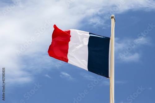 French flag on pole with blue sky and white clouds